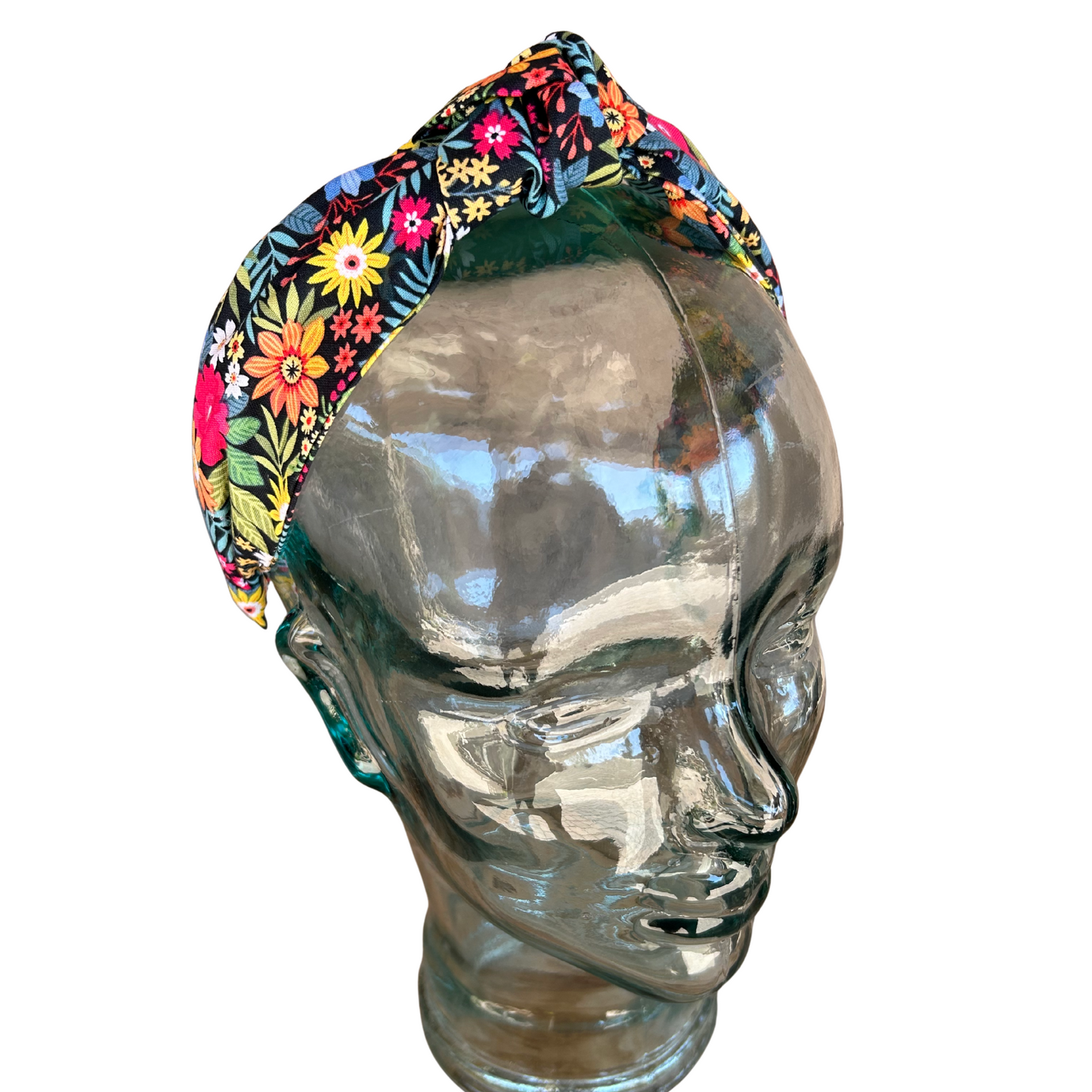 Colorful floral-patterned headband on a glass mannequin head against a white background