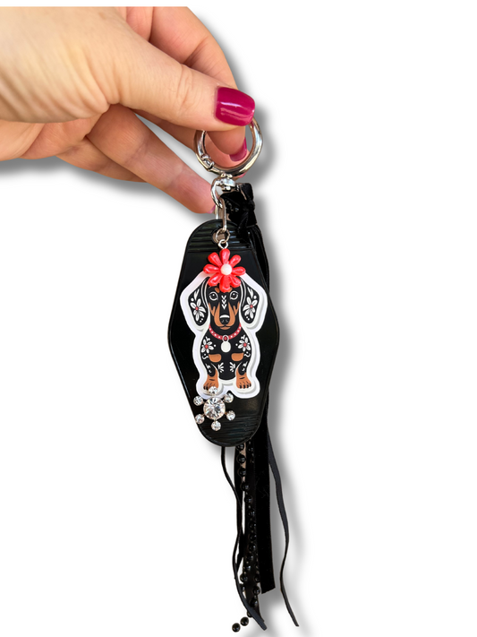 Keychain with a dachshund dog design held by a hand on a white background