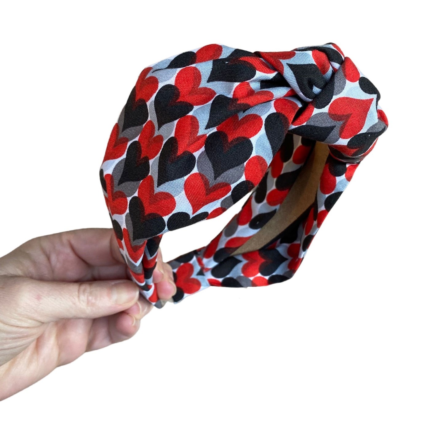 Headband with random hearts that are grey, black and red throughout. Top knot style