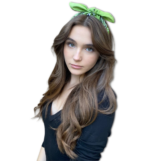 Woman with long brown hair wearing a green headband on a white background