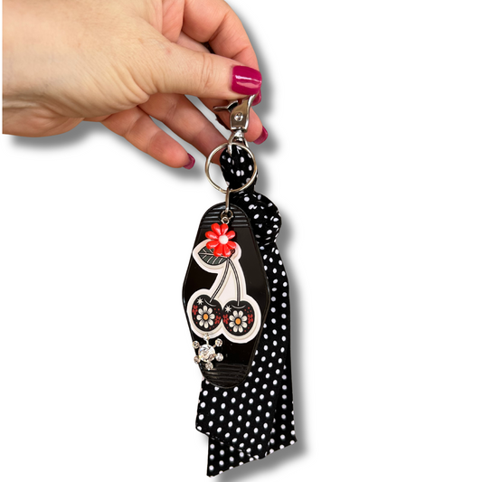 Hand holding a decorative keychain with skull design on a white background
