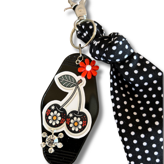 Black keychain with floral design and polka dot ribbon on a white background