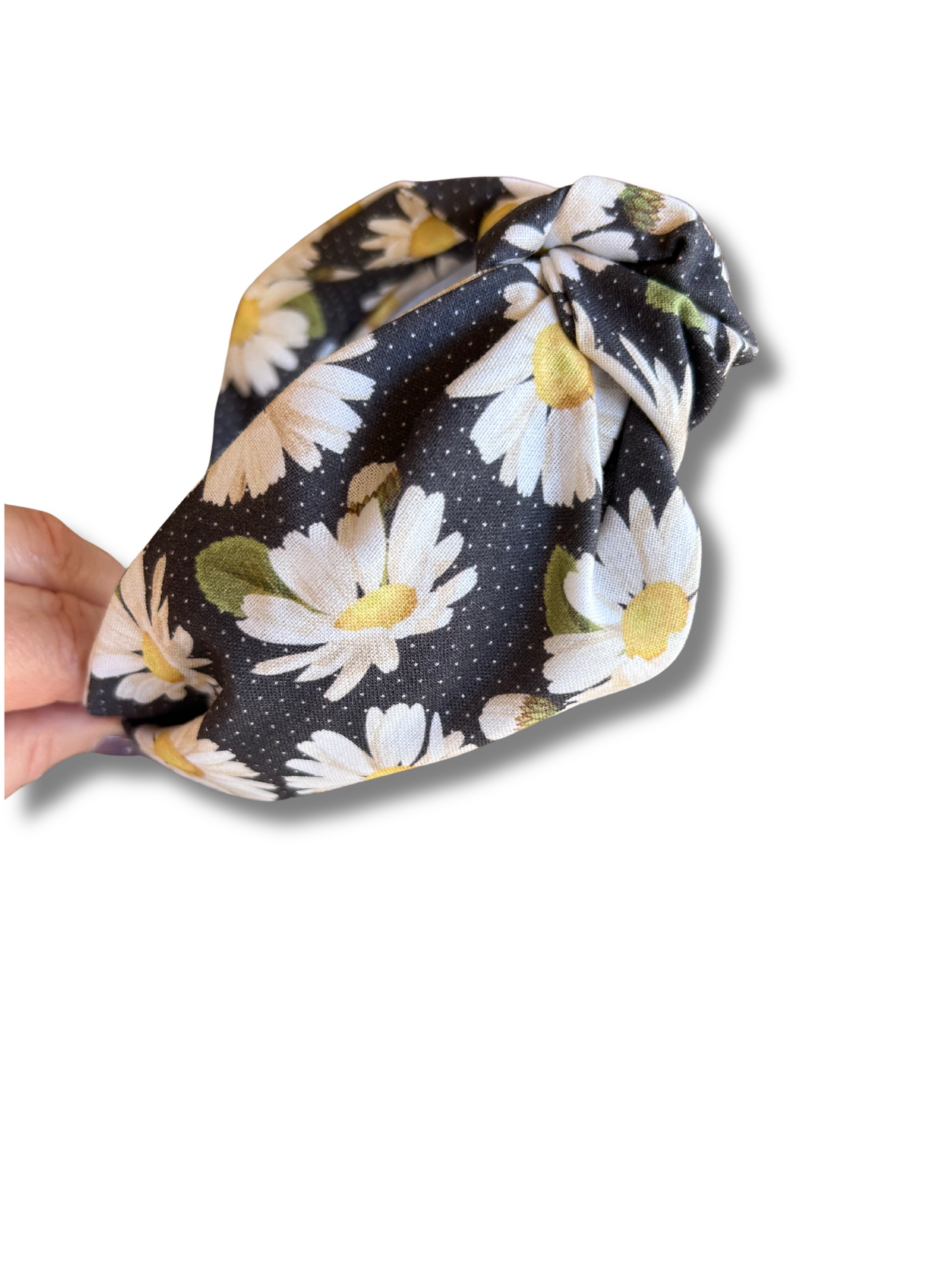 Daisy Floral-patterned headband held by a hand on a white background