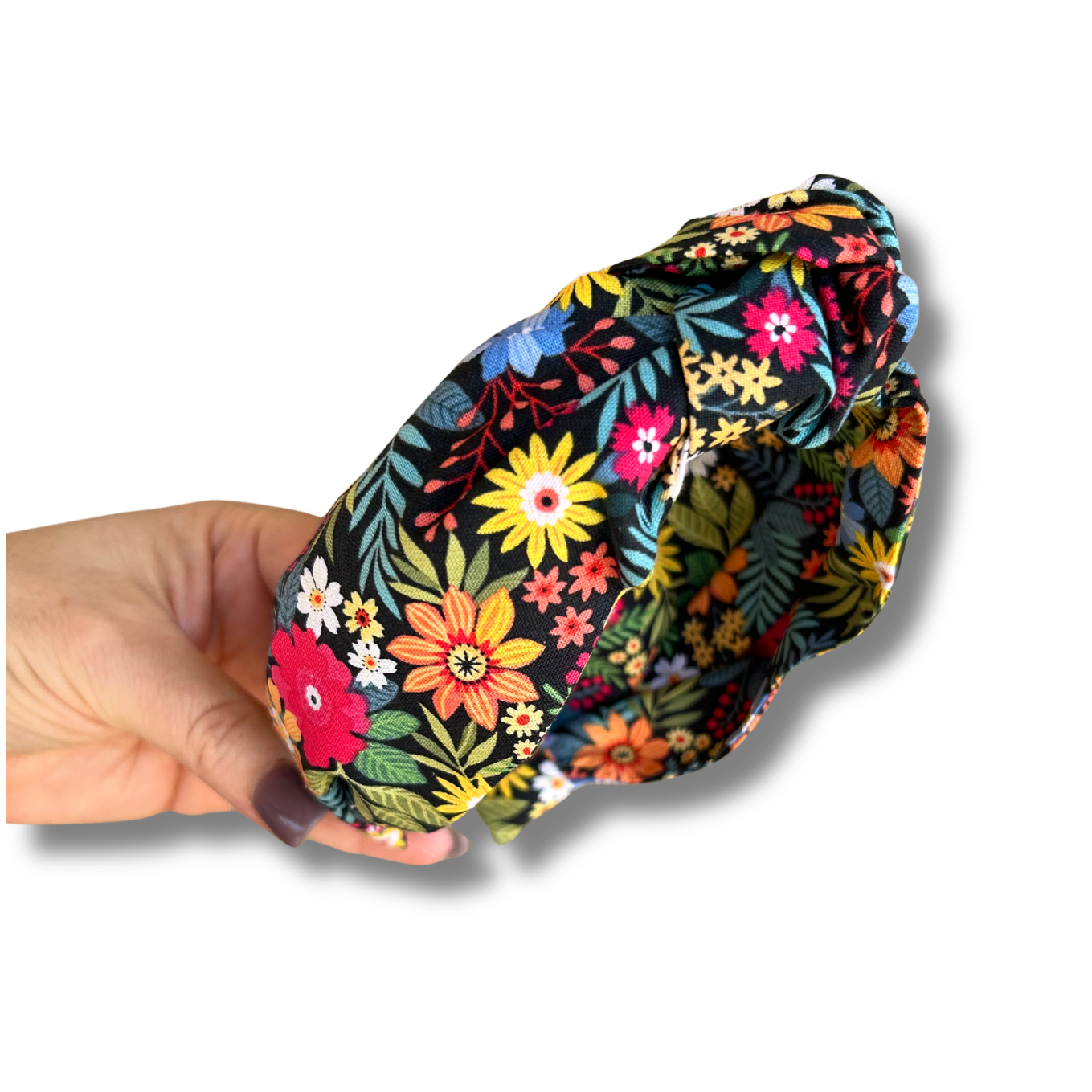 Colorful floral-patterned headband held by a hand on a white background