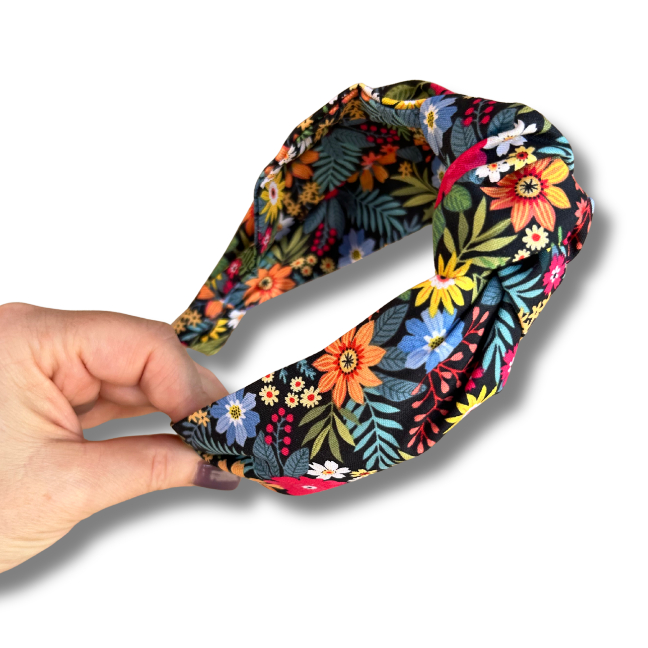 Hand holding a colorful floral headband against a white background
