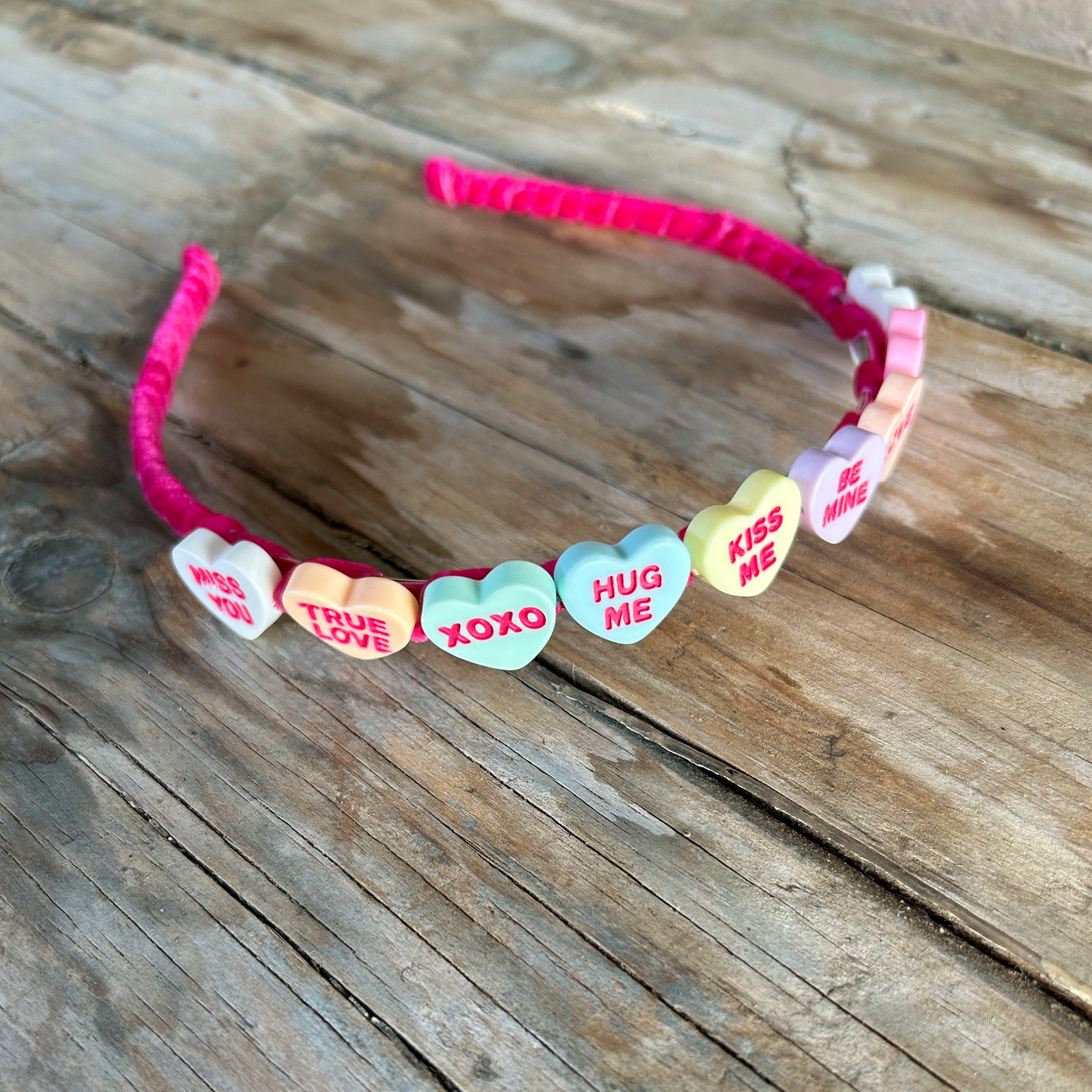 HEADBAND with heart-shaped candy charms on a wooden surface