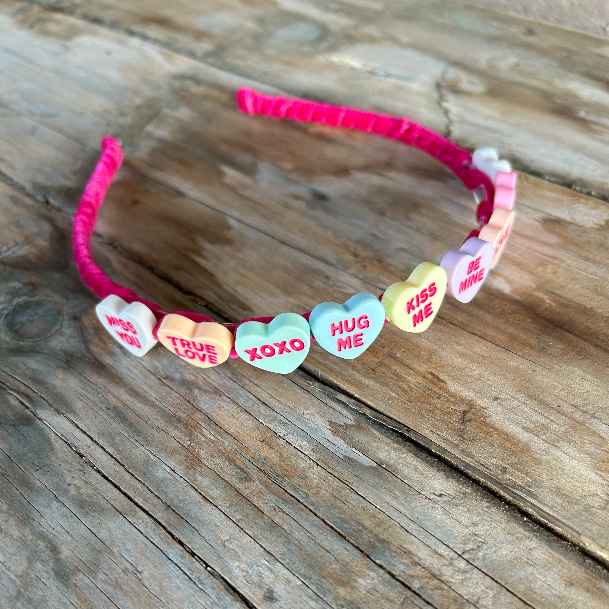 HEADBAND with heart-shaped candy charms on a wooden surface