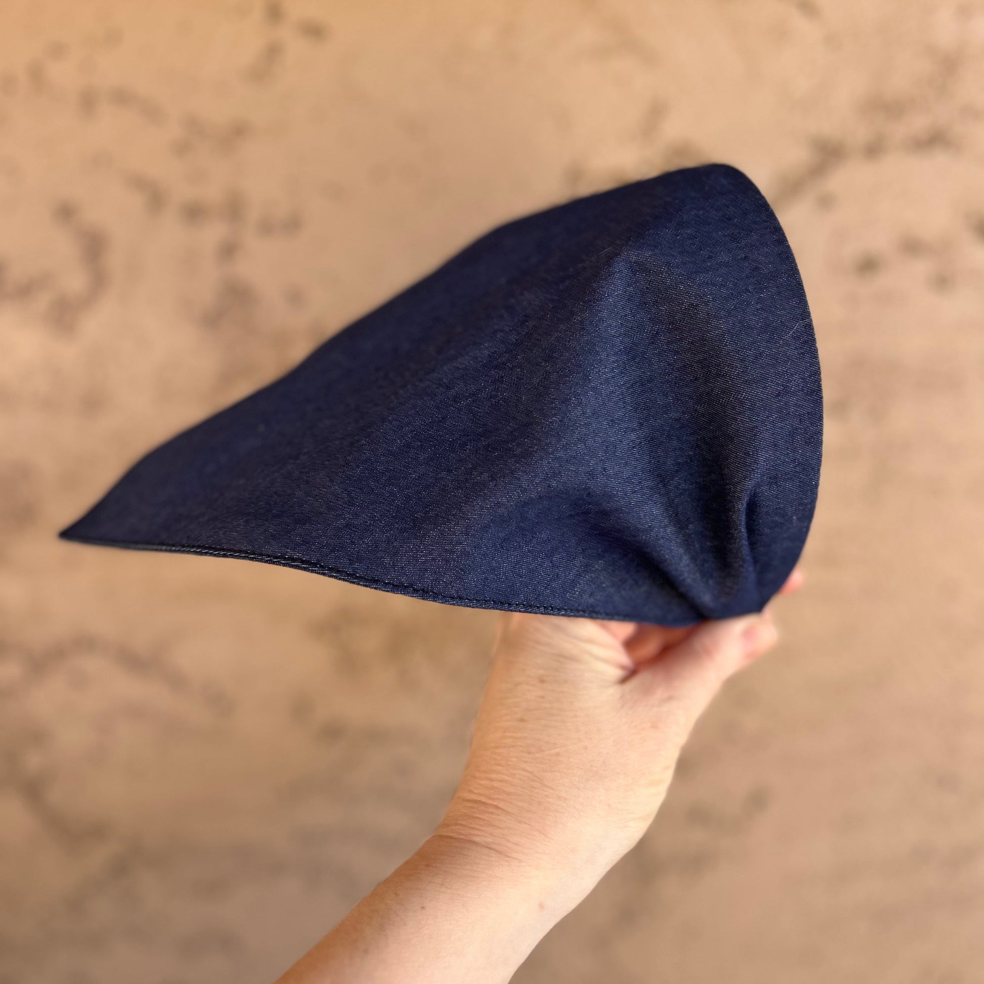 Hand holding a chambray cotton handkerchief head scarf attached to a headband