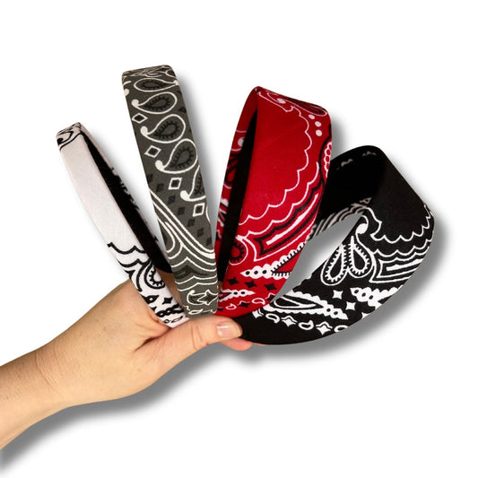 Three bandanas with different patterns held by a hand on a white background