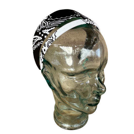 Black and white patterned headband on a clear glass mannequin head against a white background
