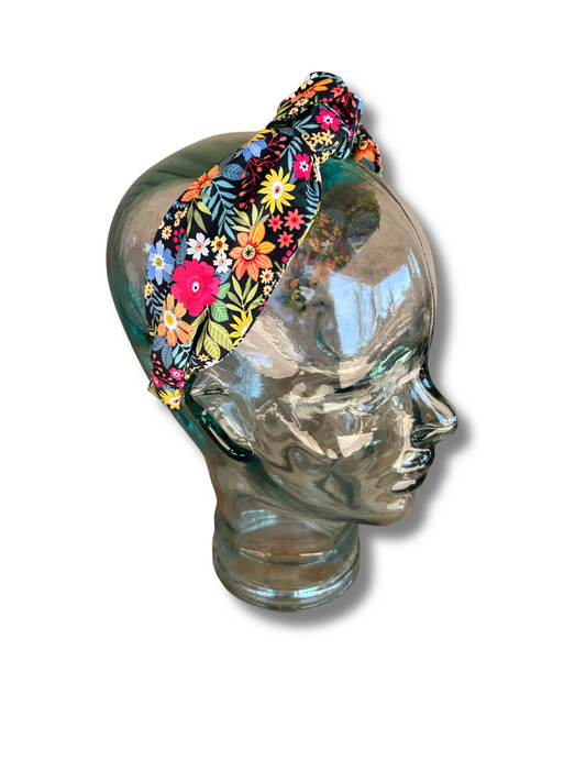 Colorful floral headband on a glass mannequin head against a white background