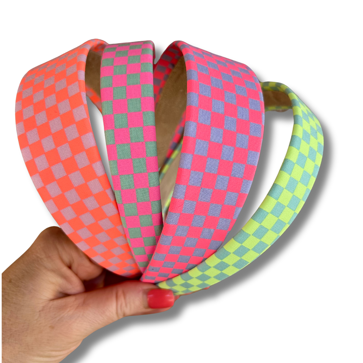 Three colorful checkered headbands held by a hand on a white background