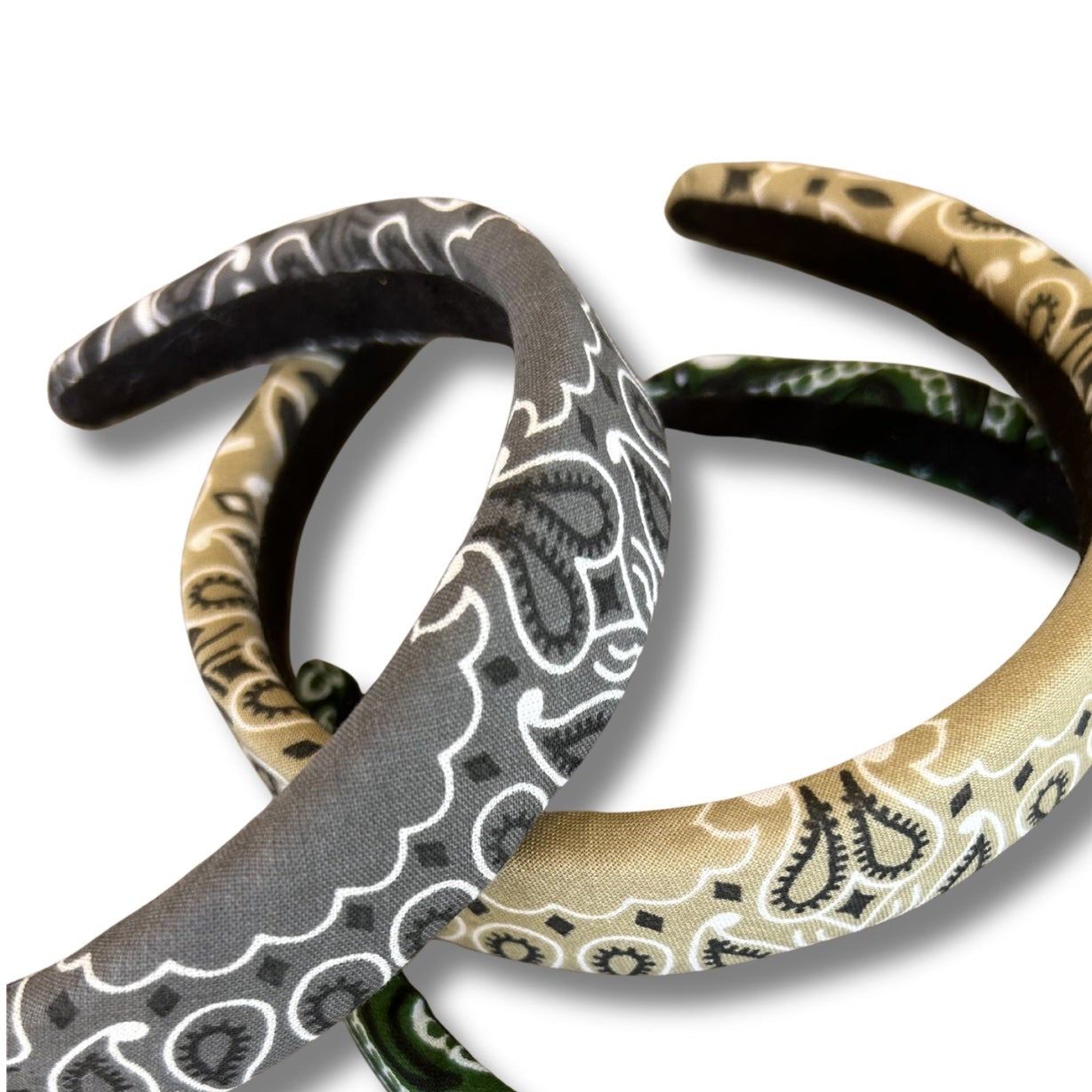 Three patterned headbands in green, black, and beige on a white background