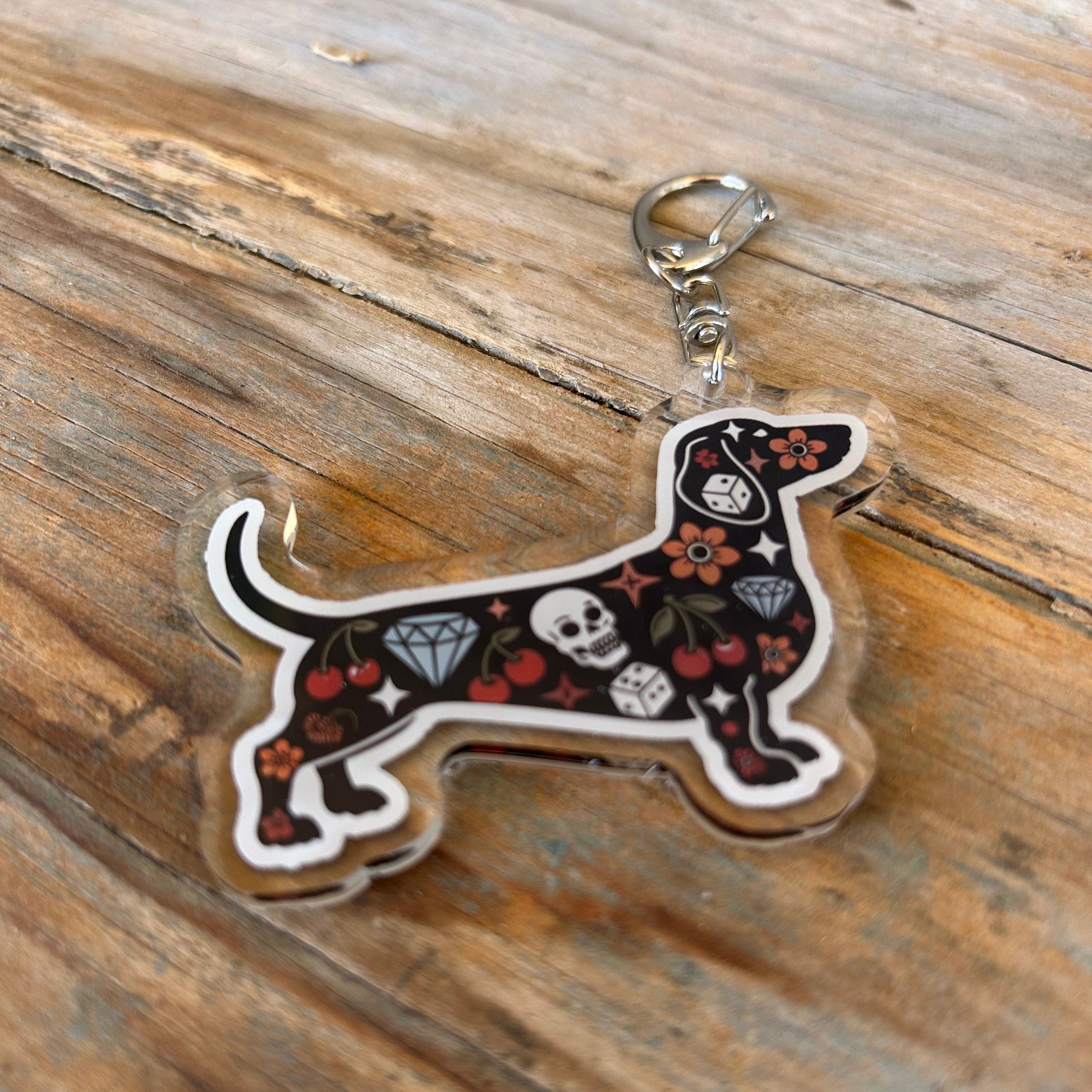 Dog-shaped keychain with black design on a wooden surface