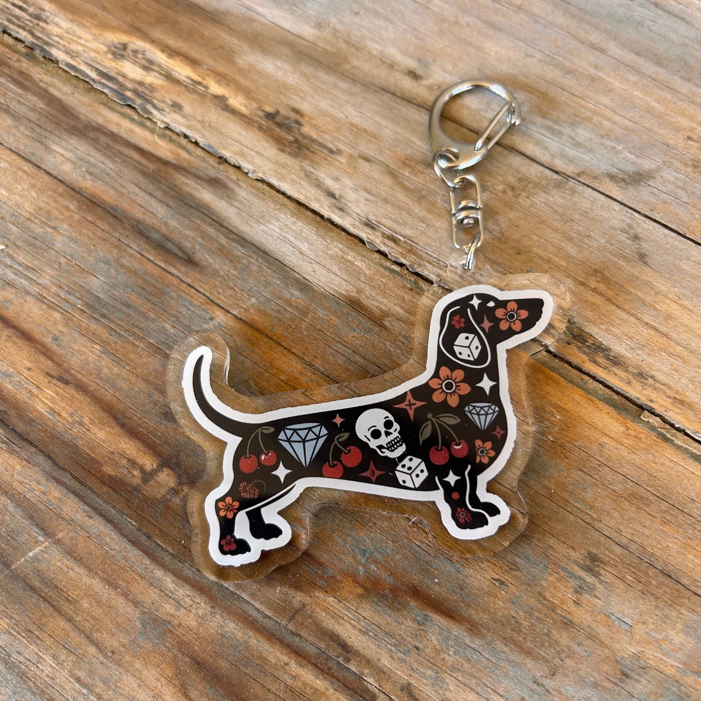 Keychain shaped like a dachshund with decorative patterns on a wooden surface