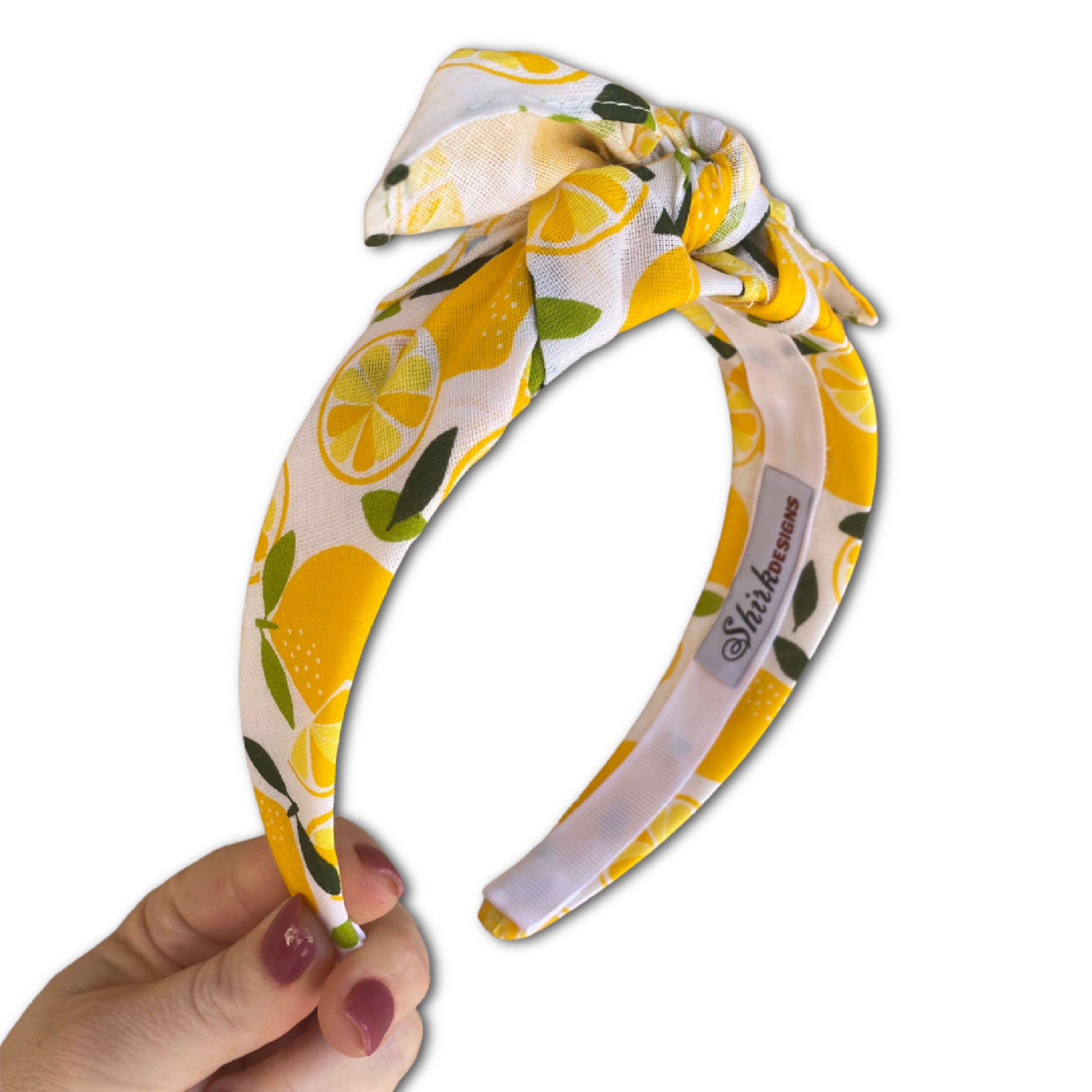 Headband that has large yellow lemon print with a white background. Tied off center at the top