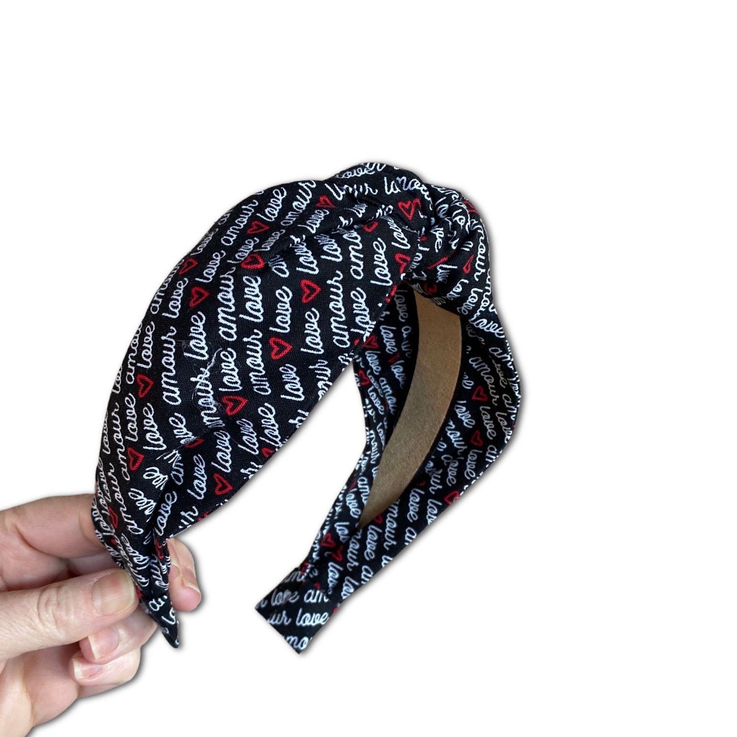 headband that features a graphic print that says "love" and "amour" with little red hearts. themed for valentines day