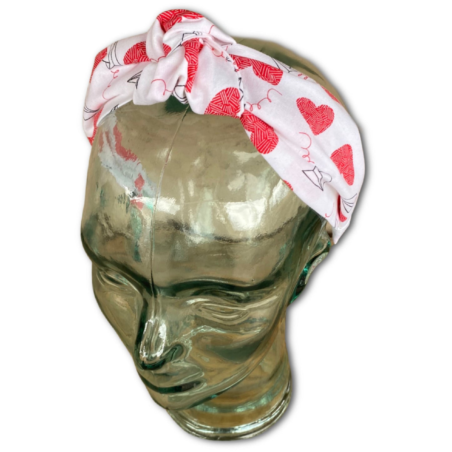 headband that has a knot at top. made with a cotton print that is white with red large hearts and paper airplane outlines