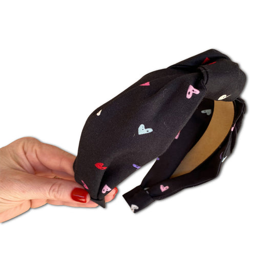 Headband with multi colored hearts through out. The fabric has a black background