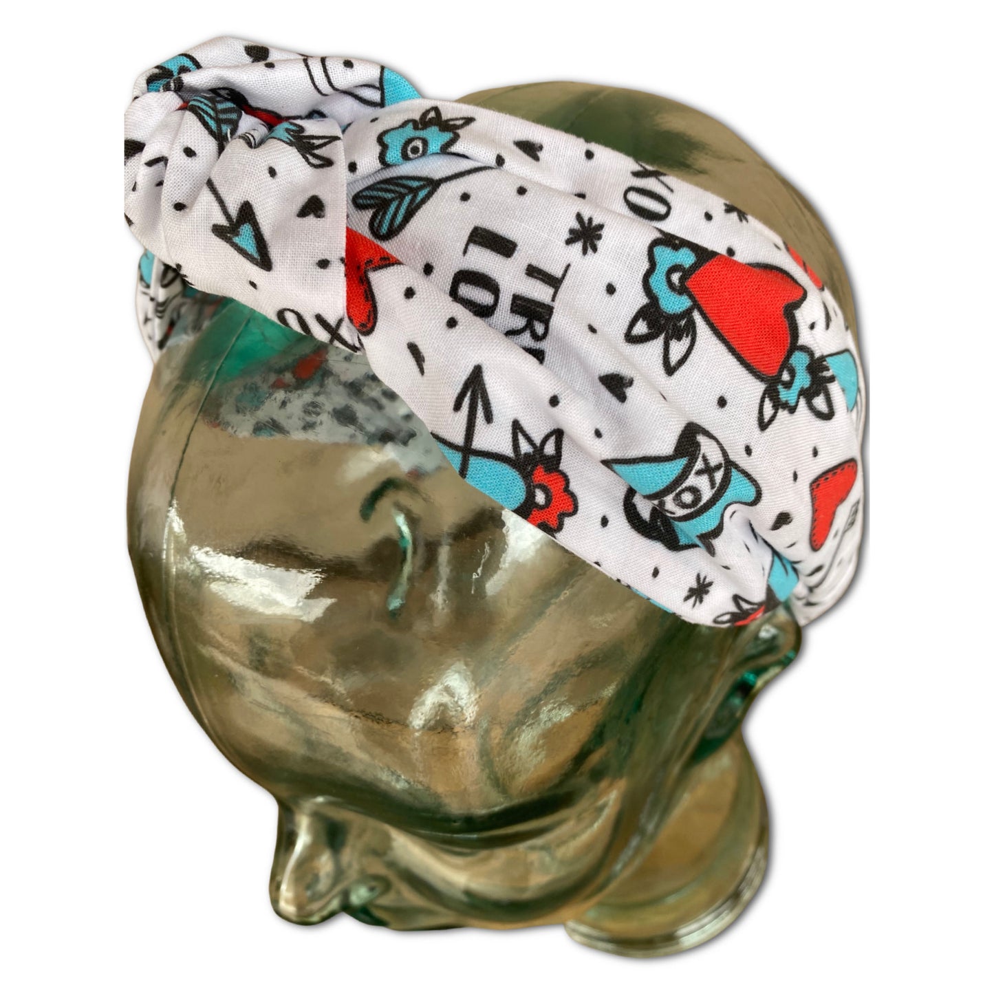 Model mannequin wearing a headband with a knot at top. Fabric is a tattoo print with hearts, keys and locks.  Red and Turquoise colors and a white background.