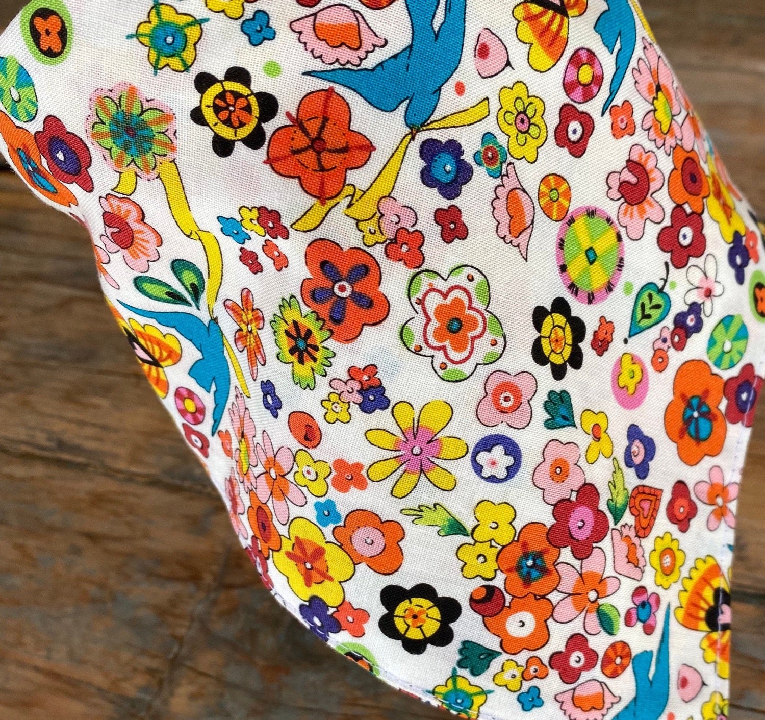 Close up of the floral print used to make the head scarf headband. brightly colored flowers and sparrow bird with ribbons