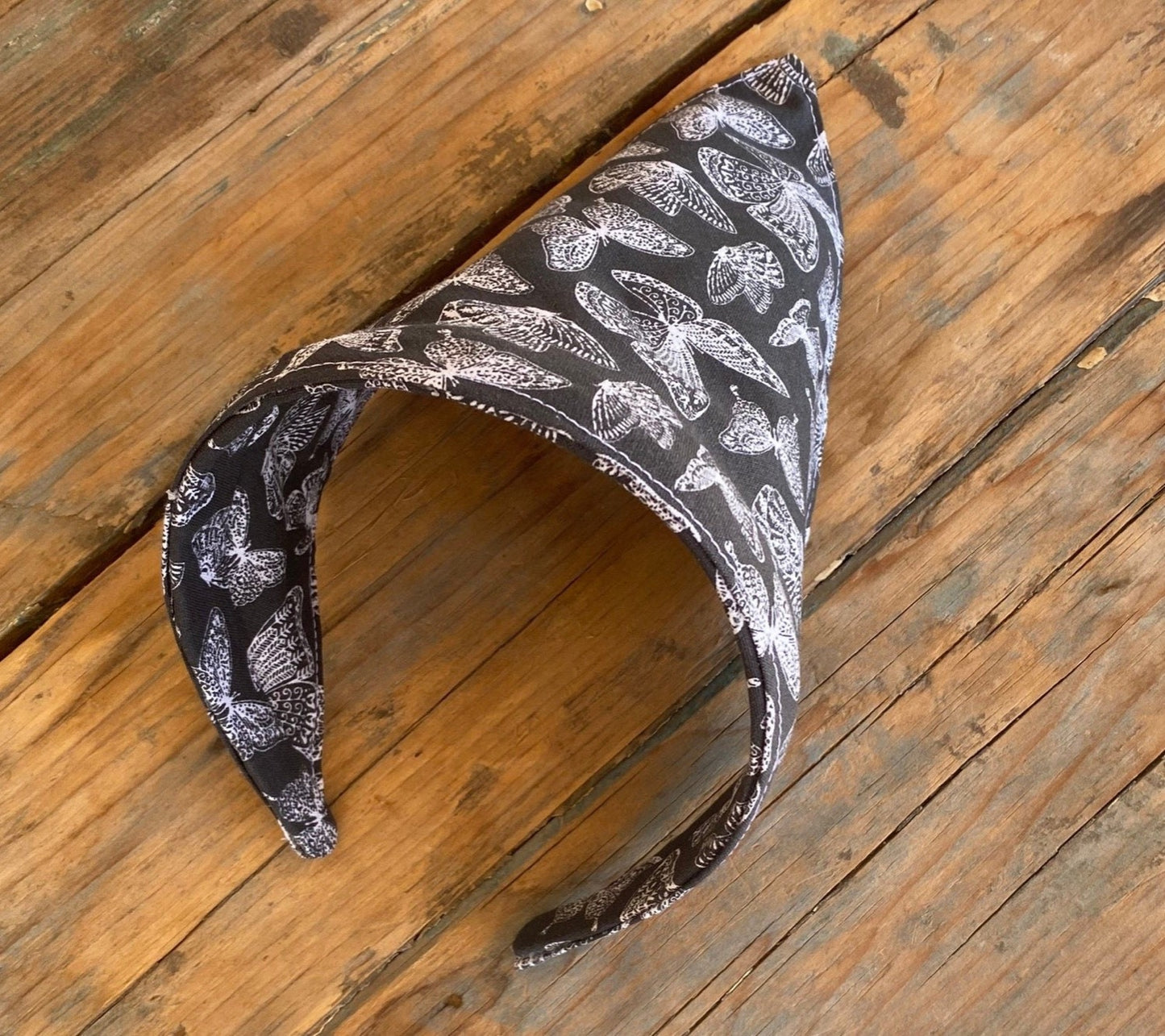 No Tie head scarf design that features a butterfly print. butterflies are white outlines and the background is a charcoal grey.